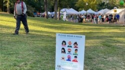 Signs are situated along the walking path of Freedom Park urging festival goers to mask up, though few were seen wearing face coverings. (Salim Fayeq/VOA)