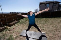 FILE - In this April 29, 2020, file photo, Olympic javelin thrower Kara Winger uses a cable system to simulate throwing a javelin as she trains outside her home in Colorado Springs, Colo.
