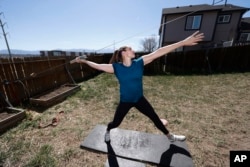 FILE - In this April 29, 2020, file photo, Olympic javelin thrower Kara Winger uses a cable system to simulate throwing a javelin as she trains outside her home in Colorado Springs, Colo.
