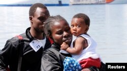 FILE - A woman holds a baby after disembarking from "Vos Prudence" Offshore Tug Supply ship as they arrive at the harbour in Naples, May 28, 2017.
