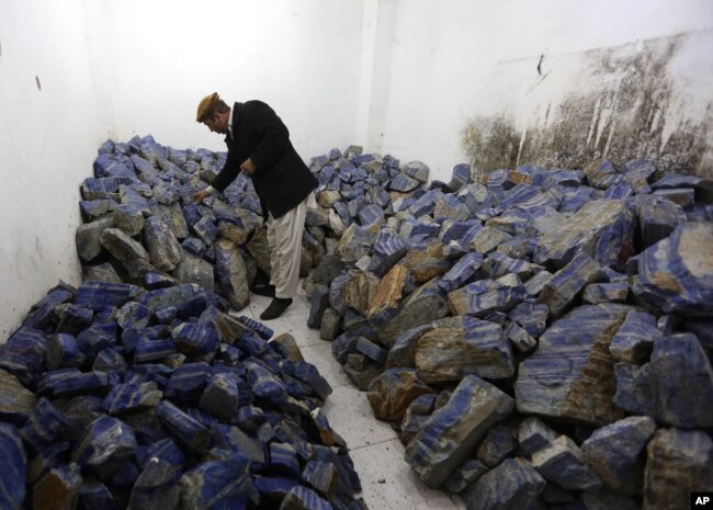 FILE - An Afghan businessman checks lapis lazuli at his shop in Kabul, March 28, 2016. The brilliant blue stone, prized for millennia, is found almost exclusively in Afghanistan and is a key part of the nation's mineral wealth.