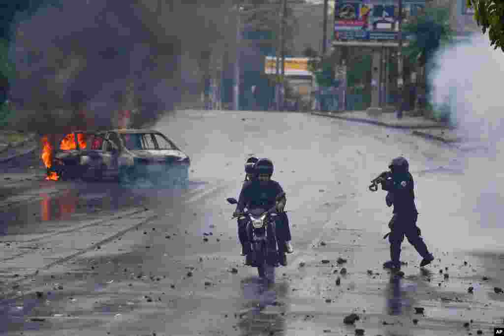 A police officer aims his shotgun at two men riding a motorcycle during a protest against Nicaragua&#39;s President Daniel Ortega, in Managua, Nicaragua, May 28, 2018. Violence returned to Nicaragua when riot police confronted protesters, and students seized a university.