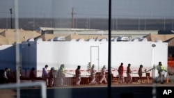 FILE - In this Dec. 13, 2018 photo, migrant teens walk in a line through the Tornillo detention camp in Tornillo, Texas. The Trump administration says it will keep the tent city holding more than 2,000 migrant teenagers open through early 2019. 