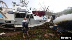 Local resident Bradley Mitchell inspects the damage to a relative's boat after it smashed against the bank after Cyclone Debbie passed through the township of Airlie Beach, located south of the northern Australian city of Townsville, March 29, 2017. 