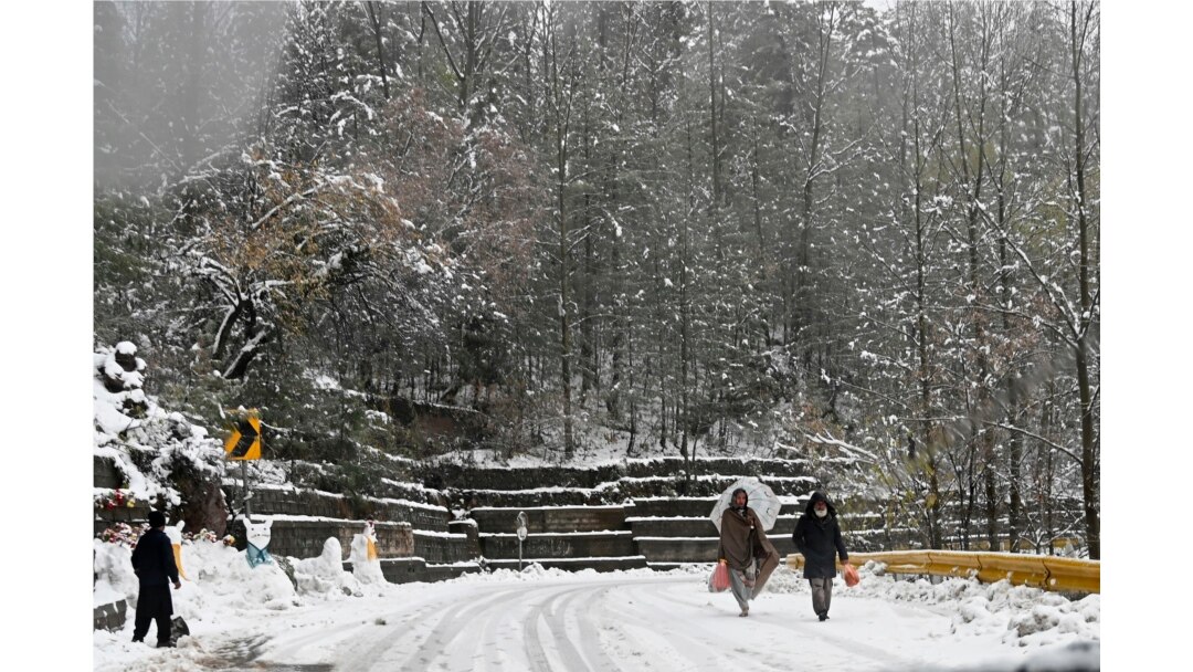 Orang-orang berjalan di jalan yang tertutup salju saat salju turun di Murree, sekitar 65 km utara Islamabad pada 12 Desember 2020. (Foto: AFP/Aamir Qureshi)