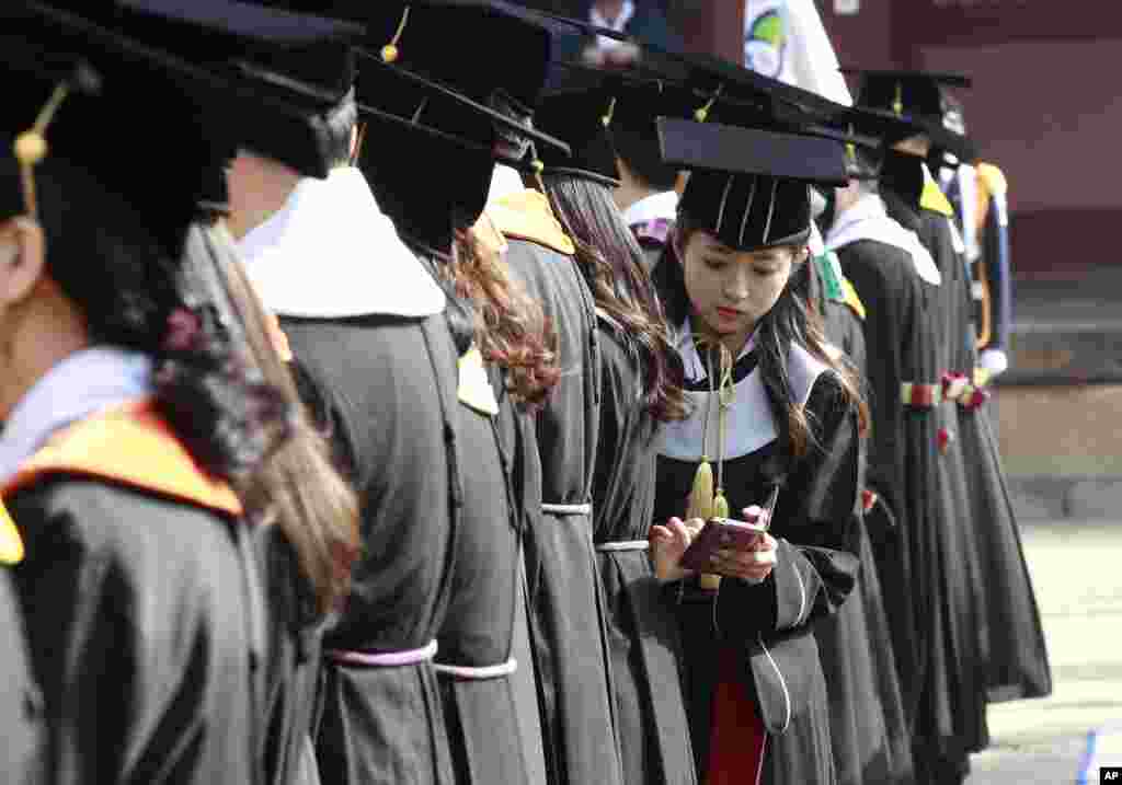 한국 서울 성균관대학교 졸업식에서 한 여학생이 스마트폰을 보고 있다.