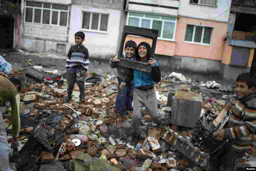 Bulgarian Roma kids react to being photographed as they salvage materials from a demolished shack in a Roma suburb in the city of Plovdiv. Municipal authorities started demolishing some 50 illegally built shacks, houses and shops in the suburb.