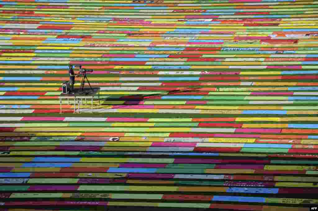 A cameraman films on long multi-colored cloths displayed on the pitch of the Anoeta stadium. The cloth strips represent a giant ballot box during a demonstration organized by pro-independence platform &lsquo;Gure Esku Dago&rsquo; (It&#39;s in our hands) in San Sebastian, Spain, June 21, 2015.