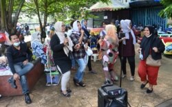 Sekelompok warga berkumpul untuk karaoke di luar ruangan di sebuah taman di pinggiran Jakarta, ketika pemerintah melonggarkan pembatasan COVID-19 dengan penurunan infeksi baru-baru ini, 19 September 2021. (Foto: GOH CHAI HIN / AFP)