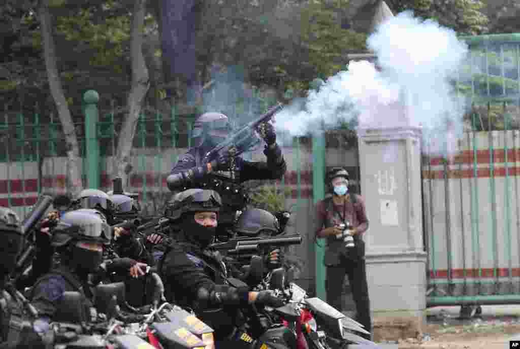 A police officer fires his tear gas launcher during a protest against the new Job Creation Law approved by Parliament last week in Jakarta, Indonesia, Tuesday, Oct. 13, 2020. Thousands of conservative Muslims marched in Indonesia's capital on Tuesday dema