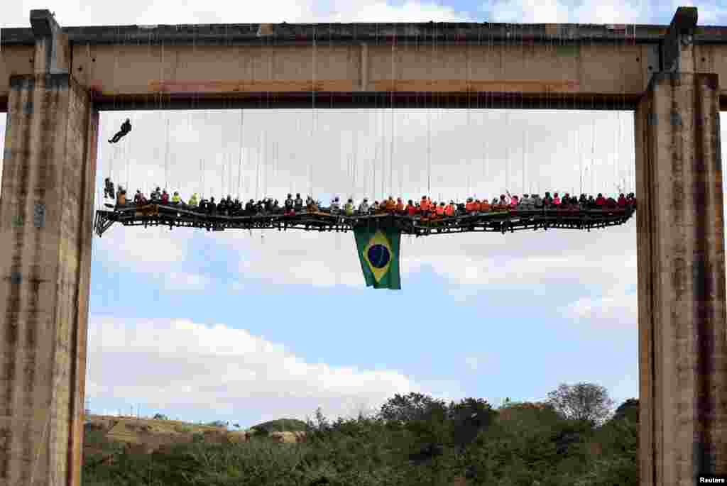 A group of 90 people eat at a barbecue as they sit on a table while suspended under a bridge using rapelling techniques in Limeira, Brazil, July 30, 2017.