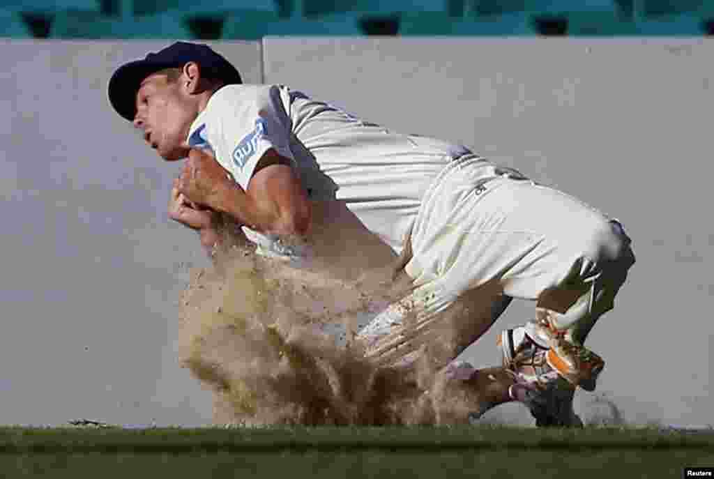 Cricket Australia Invitational XI player Daniel Hughes kicks up dirt as he takes a catch to dismiss England&#39;s Kevin Pietersen for 57 runs during their warm-up match at the Sydney Cricket Ground, Australia.