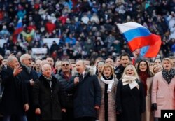 Russian President Vladimir Putin, center, and other guests sing Russia's national anthem during a massive rally in his support as a presidential candidate at the Luzhniki stadium in Moscow, March 3, 2018.