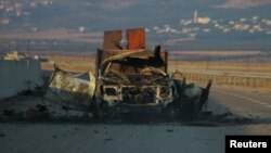 FILE - A damaged military vehicle is seen along a road in Freikeh village after fighters from an Islamist coalition took control of the village from forces loyal to Syria's President Bashar al-Assad in Idlib, Syria, July 30, 2015.