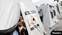 A Venezuelan woman holds her baby inside a tent outside a gym which has been turned into a shelter for Venezuelans and is run by Civil Defense with meals provided by Evangelical churches in Boa Vista, Brazil, Nov. 17, 2017.