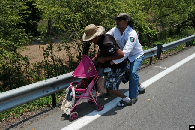 A Central American migrant pushing a child in a baby carriage is detained by a Mexican immigration agent from behind on the highway to Pijijiapan, Mexico, April 22, 2019.
