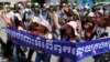 In this file photo, Cambodian activists shout slogans during a march toward the National Assembly with the banner that reads "Absolutely against the corruption in the society," in Phnom Penh, Cambodia, Thursday, May 29, 2014.