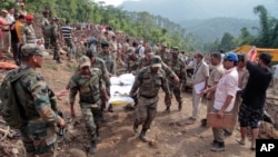 Army soldiers and rescue workers recover bodies of landslide victims even as they try to pull out two buses that were covered in mud after a landslide in Urla village, Himachal Pradesh state, India, Aug. 13, 2017. 