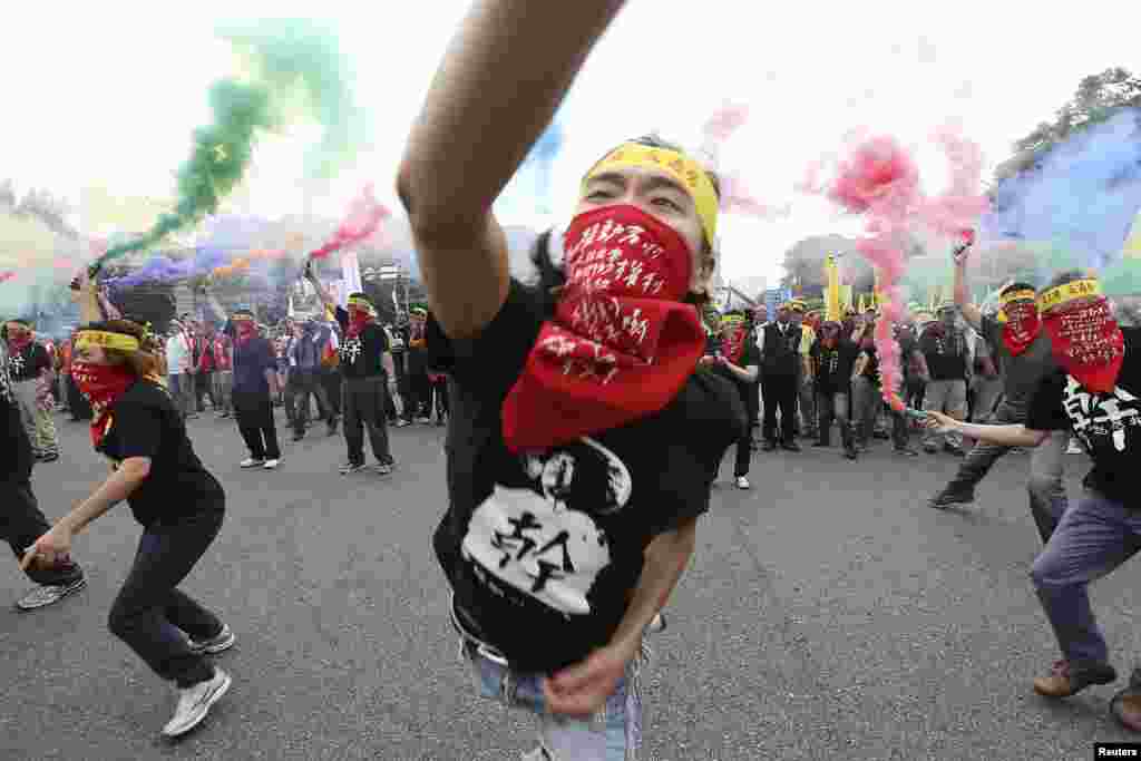 Warga melemparkan granat asap dalam berbagai warna pada acara demonstrasi Hari Buruh tahunan di depan Kantor Kepresidenan di Taipei, Taiwan. Ribuan orang berbaris untuk menuntut upah lebih tinggi dan hak-hak buruh. Kepala spanduk bertuliskan: &quot;pendekkan jam kerja; hapuskan kelelahan berlebihan.&quot;