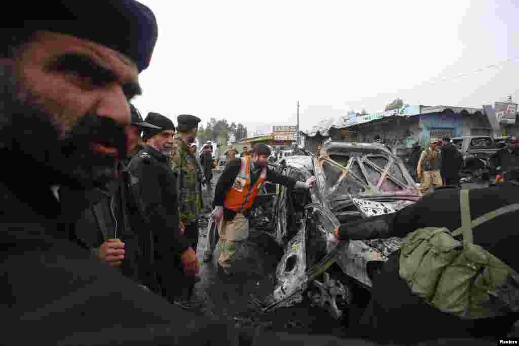 Police officers try to move a car, which was damaged during a bomb attack at Fauji Market in Peshawar December 17, 2012. The blast in the market in northwest Pakistan on Monday killed at least 15 people, a security official said. The official said at leas