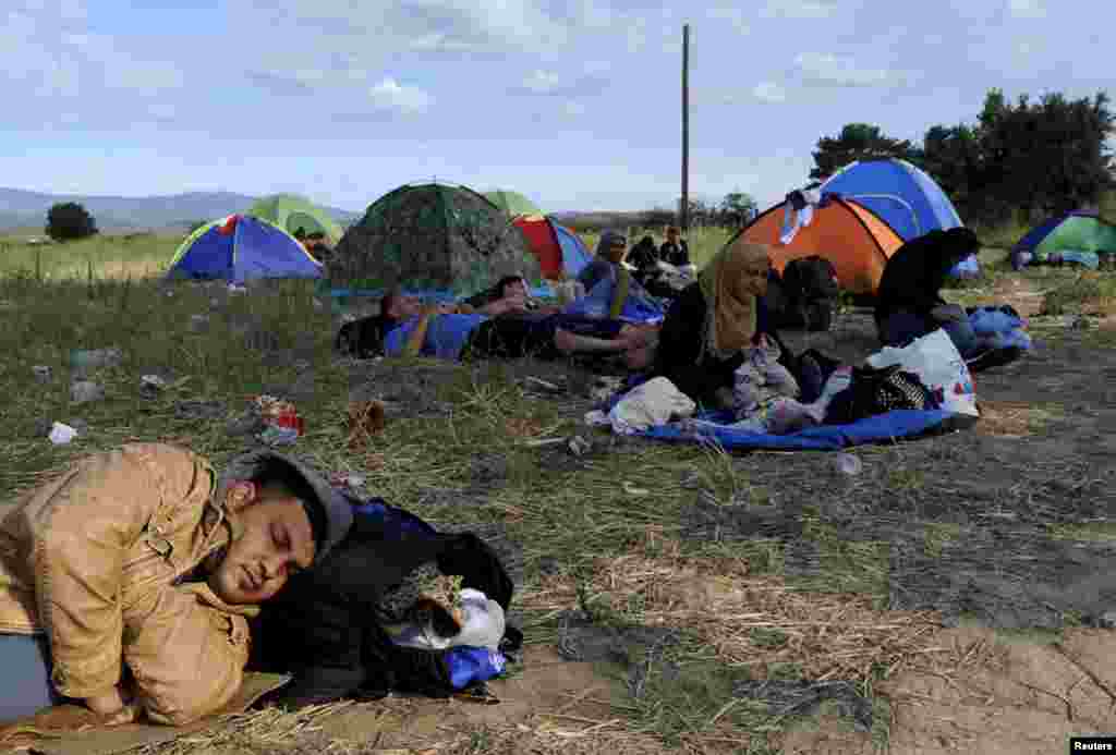 Migrants rest on a field at the border between Greece and Macedonia, Aug. 21, 2015.