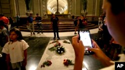 FILE - People stand around the tomb of late Spanish dictator Francisco Franco, inside the basilica at the Valley of the Fallen monument, near El Escorial, outside Madrid, Spain, Aug. 24, 2018. 
