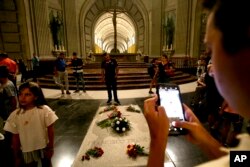People stand around the tomb of former Spanish dictator Francisco Franco inside the basilica at the the Valley of the Fallen monument near El Escorial, outside Madrid, Spain, Aug. 24, 2018.