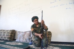 Heza, pejuang Yazidi dari Unit Perempuan Shengal (YPS), mempersiapkan senapannya di rumah yang ditinggalkan yang digunakan sebagai markas YPS di Al-Meshleb, pinggiran timur Raqa, 18 Juli 2017. (BULENT KILIC / AFP)