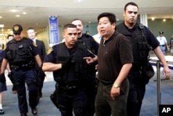 FILE - Dr. Yang Jianli, second from right, president of Initiatives for China, is escorted by United Nations security after staging a demonstration inside the lobby of the United Nations headquarters, Tuesday, Aug. 31, 2010.