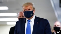 President Donald Trump wears a mask as he walks down a hallway during his visit to Walter Reed National Military Medical Center in Bethesda, Md., July 11, 2020.