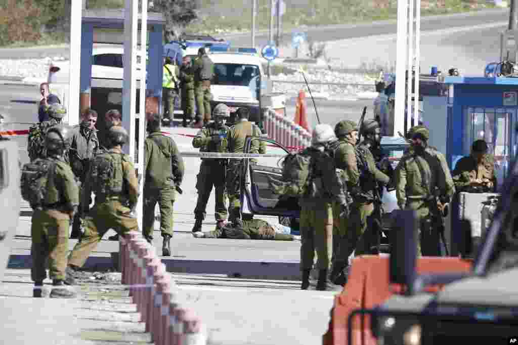 Israeli security forces inspect the body of a Palestinian identified as Amjad Sukkari, at the checkpoint between the city of Ramallah and Jewish settlement of Beit El in the West Bank.&nbsp;Sukkari opened fire at a West Bank checkpoint and wounded three people, the Israeli military said.&nbsp;