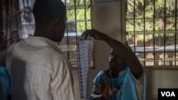 Umukozi mu batunganya amatora asigurira uwutora muri Freetown, Sierra Leone, Itariki 7/03/2018. (Photo: Jason Patinkin / VOA) 