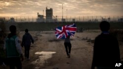 Un homme court avec le drapeau anglais dans le camp pour migrants appelé "la jungle" près Calais, France, le 25 octobre 2016.