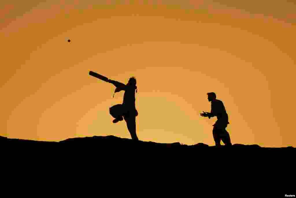 Boys are silhouetted against the setting sun while playing cricket in Karachi, Pakistan.