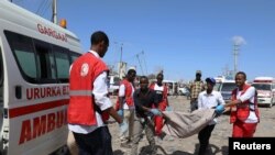 Civilians carry the body of a man killed in a car bomb explosion at a checkpoint in Mogadishu, Somalia, Dec. 28, 2019.