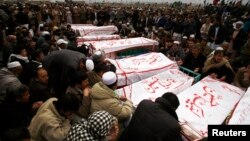 Shi'ite Muslims sit around coffins of victims killed in Saturday's bomb attack, during a funeral at a cemetery in Quetta, February 20, 2013. 