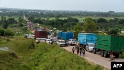 FILE —Trucks containing goods from neighboring countries are stranded on the road after the collapse of the bridge on national road number 5, in the village of Sange, South Kivu province, eastern Democratic Republic of Congo, February 29, 2024.