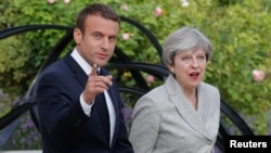 French President Emmanuel Macron escorts Britain's Prime Minister Theresa May as they arrive to speak to the press at the Elysee Palace in Paris, France, June 13, 2017.