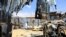 Des civils marchent près de la scène où un tir de mortier a détruit des maisons à l'extérieur d'un complexe tentaculaire qui abrite la base de la Mission de l'Union africaine en Somalie (AMISOM) à l'aéroport de Mogadiscio, en Somalie, le 25 mars 2021.