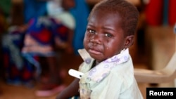 FILE - A child with a thermometer tucked in her armpit cries at a clinic in Nigeria, Aug. 14, 2013. Quackery is a problem in Nigeria, but a new database helps weed out unlicensed doctors.