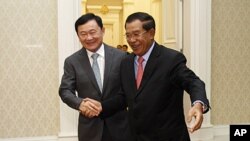 Former Thai Prime Minister Thaksin Shinawatra, left, is welcomed by Cambodian Prime Minister Hun Sen upon arrival at Peace Palace in Phnom Penh, Cambodia, September 17, 2011.