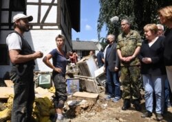 German Chancellor Angela Merkel, 2nd right, and Rhineland-Palatinate State Premier Malu Dreyer, right, talk to residents during their visit to the flood-damaged village of Schuld near Bad Neuenahr-Ahrweiler, Germany, July 18, 2021.