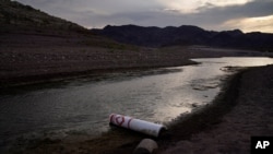 A buoy once used to warn of a submerged rock rests on the ground along the waterline near a closed boat ramp on Lake Mead at the Lake Mead National Recreation Area, Friday, Aug. 13, 2021, near Boulder City, Nev. Water levels at Lake Mead, the…