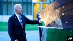 President Joe Biden touches a piece of steel from the North Tower of the World Trade Center while visiting a memorial to the September 11 terrorist attacks at NATO headquarters in Brussels, Monday, June 14, 2021. (AP Photo/Patrick Semansky)