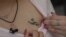 FILE - Shavit Irene, girlfriend of 21-year-old Israeli citizen Netta Epstein who died when he jumped on a grenade during the October 7 attack in southern Israel, shows off a tattoo she had made following his death in the village of Bitzaron on November 3, 2023.