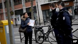 Police officers stop a pedestrian in Boulogne-Billancourt, a western suburb of Paris, France, March 18, 2020.