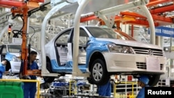 FILE - Employees work on assembling vehicles at a plant of SAIC Volkswagen in Urumqi, Xinjiang Uighur Autonomous Region, China September 4, 2018. (China Daily via REUTERS)