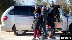 FILE - A family which claimed to be from Sudan, piles out of a Northern Taxi which drove them to the U.S.-Canada border in Champlain, New York, February 17, 2017. 