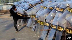 A student protester kicks the shield of riot police officers during a clash in Jakarta, Indonesia, Sept. 30, 2019.