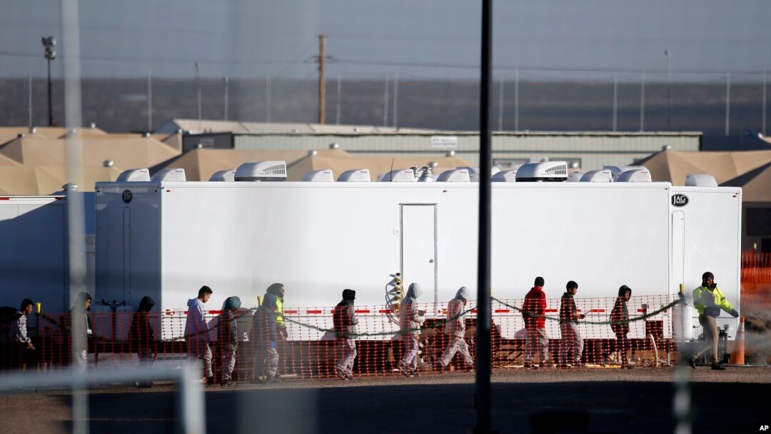 FILE - In this Dec. 13, 2018 photo, migrant teens walk in a line through the Tornillo detention camp in Tornillo, Texas. The Trump administration says it will keep the tent city holding more than 2,000 migrant teenagers open through early 2019. 